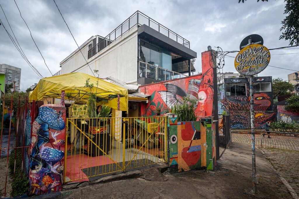 Entrada colorida de um bar com tenda amarela no Beco do Batman