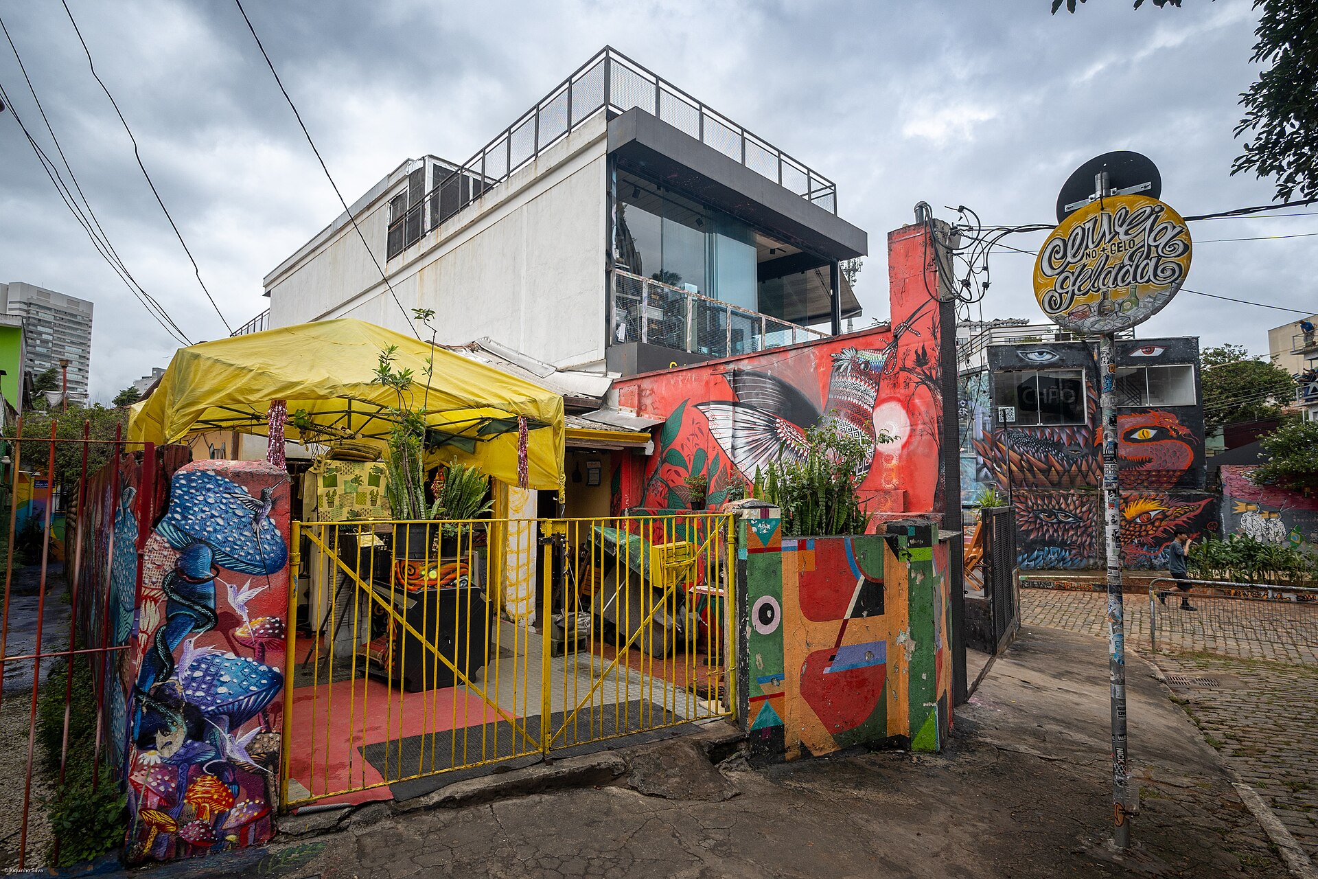 Entrada colorida de um bar com tenda amarela no Beco do Batman