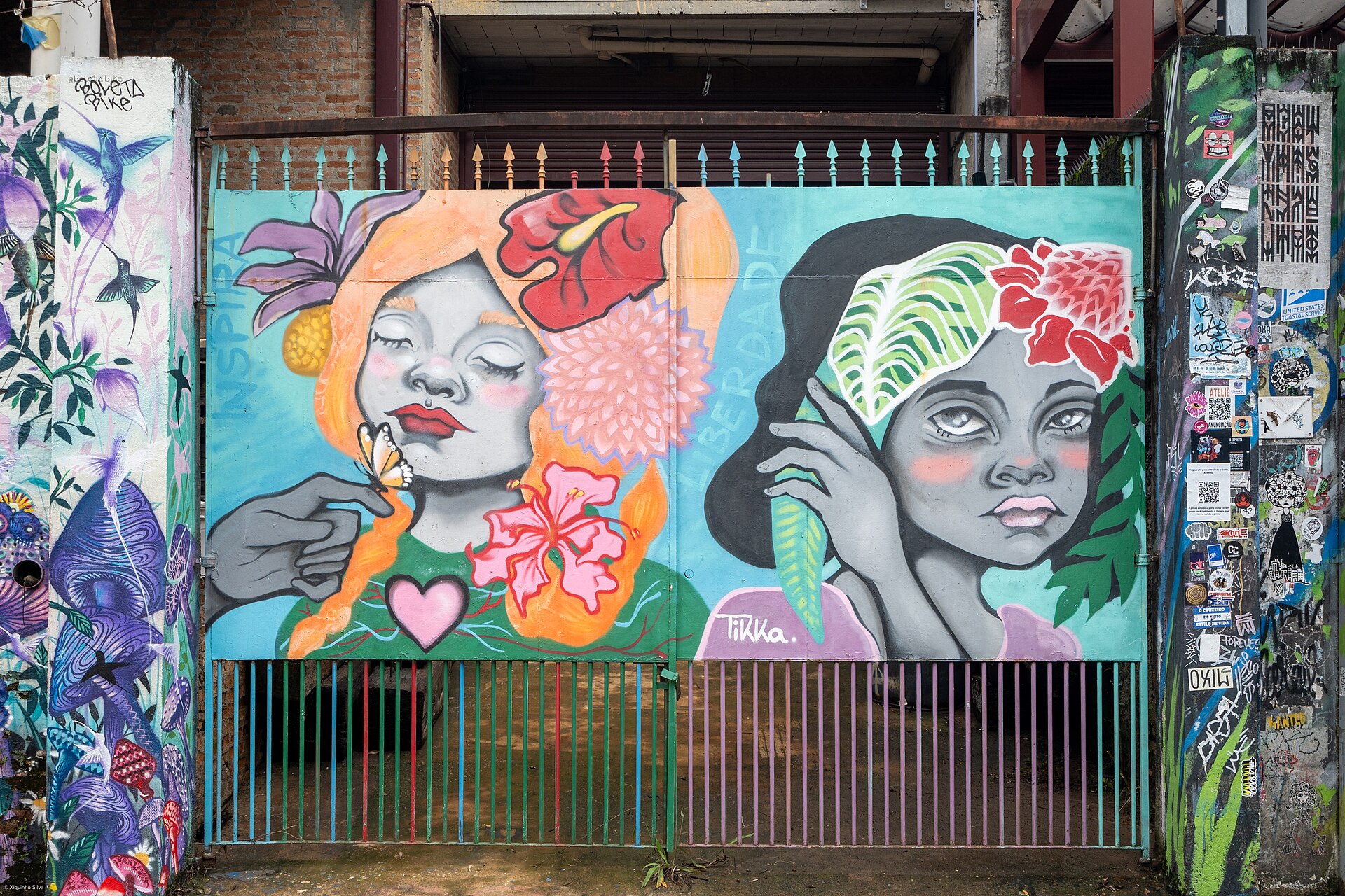 Mural colorido de rosto feminino com flores pintado em um portão no Beco do Batman
