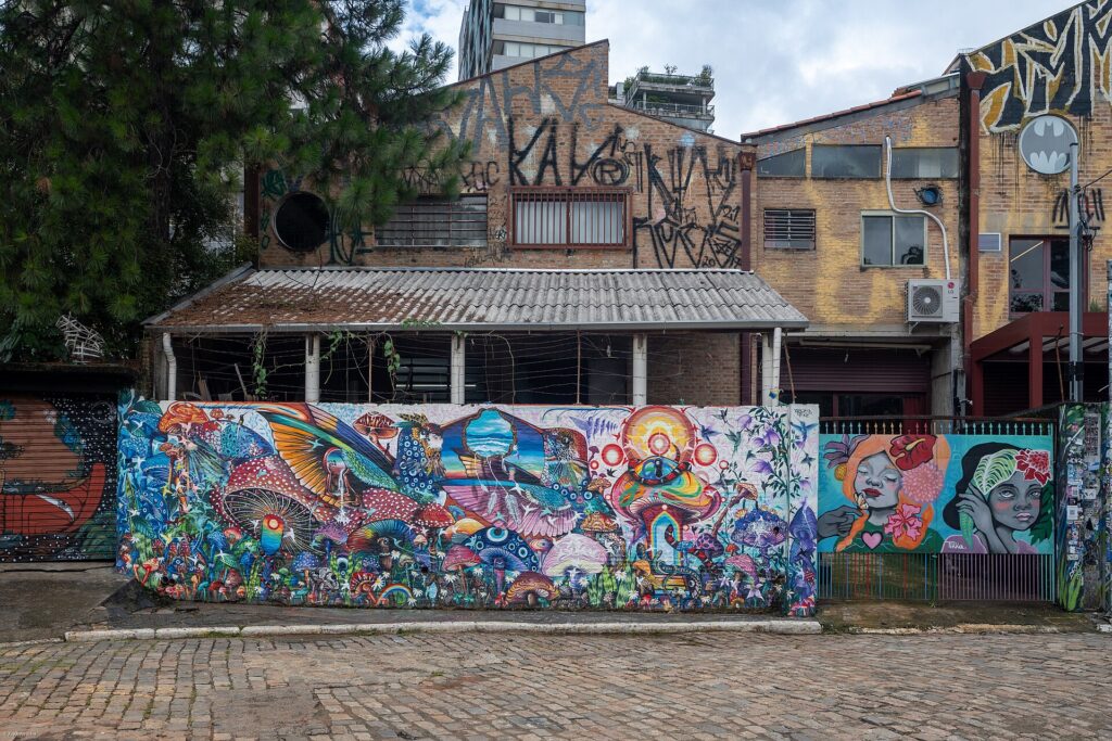 Muro longo coberto por grafite colorido no Beco do Batman