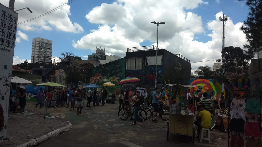 Largo do Beco do Batman com barracas de feira, guarda-sóis, bicicletas e visitantes