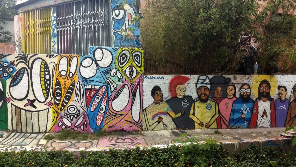 Muro do Beco do Batman com grafites coloridos e um painel de jogadores de futebol