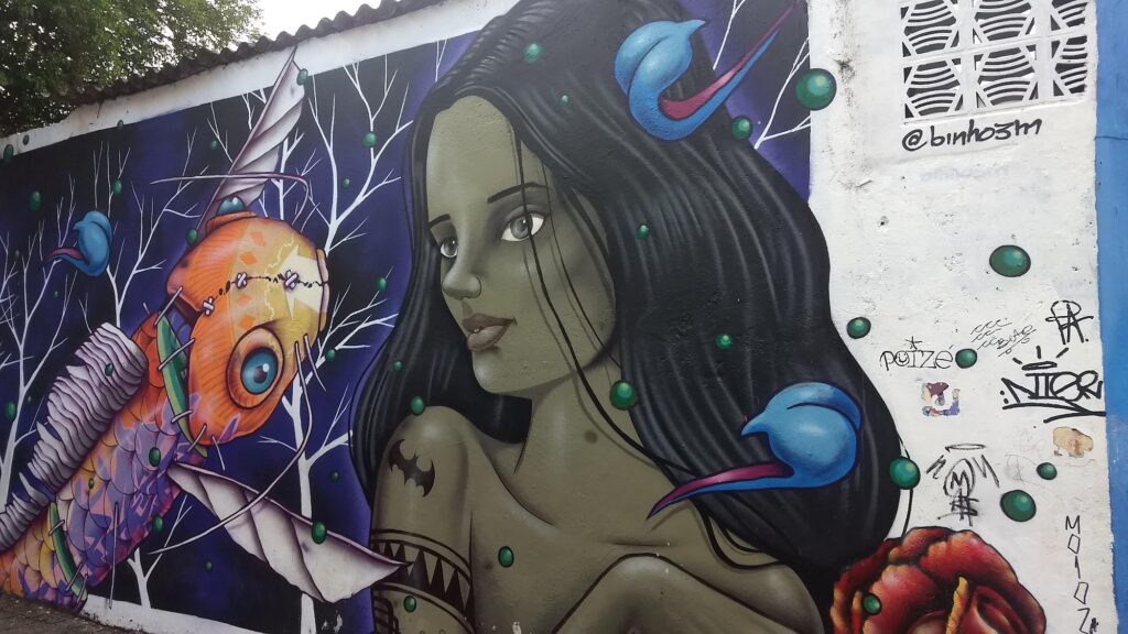 Grafite de mulher de cabelos longos cercada por peixe laranja e pássaros azuis